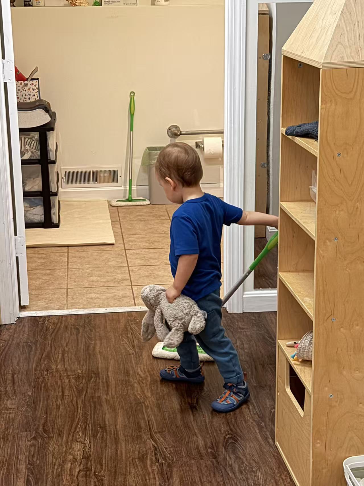 a child pushing a child-sized mop across the floor